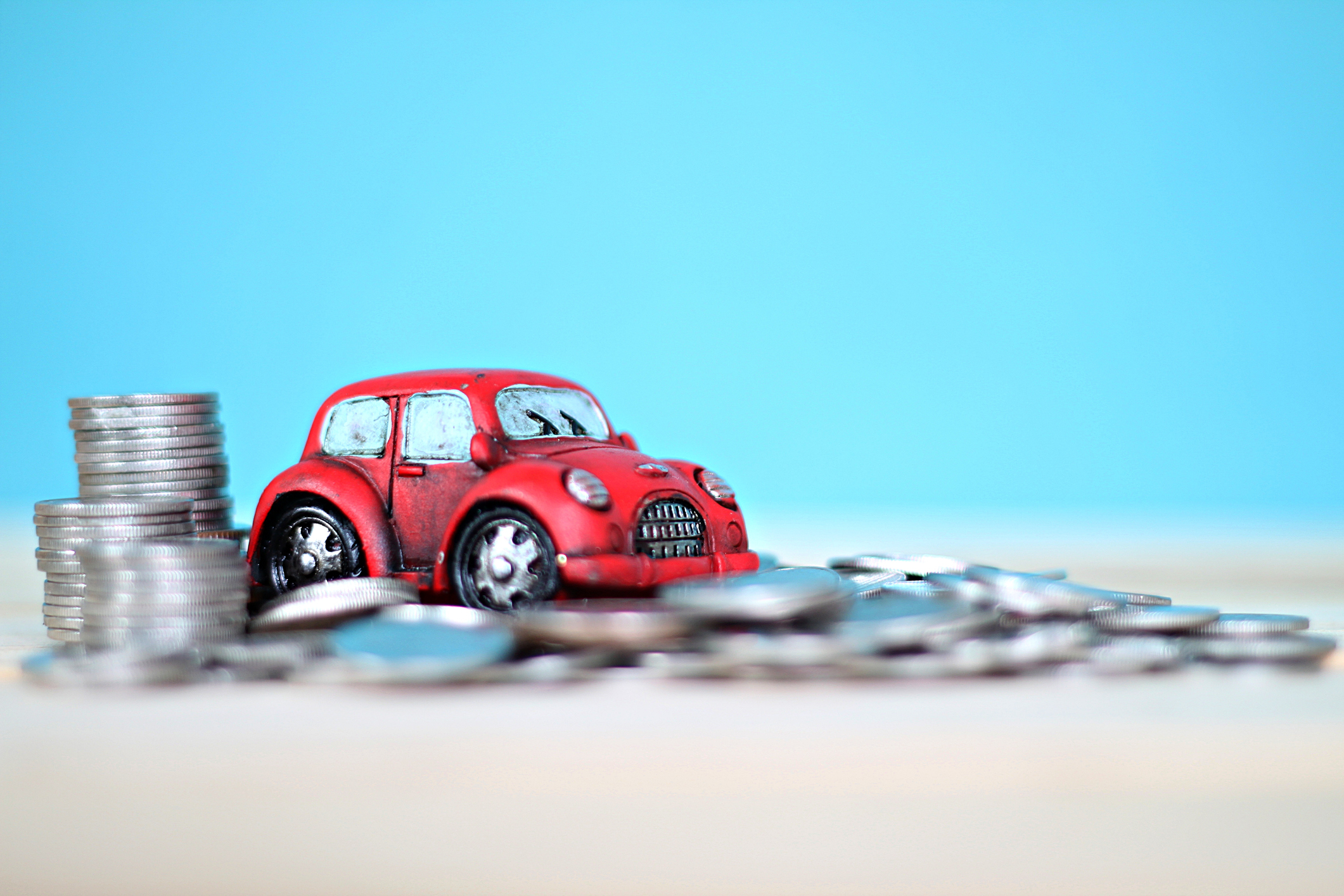 Image: Toy car driving over a pile of money.