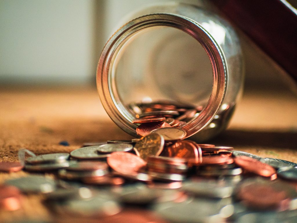 Photo of glass tipped over with coins on the table top