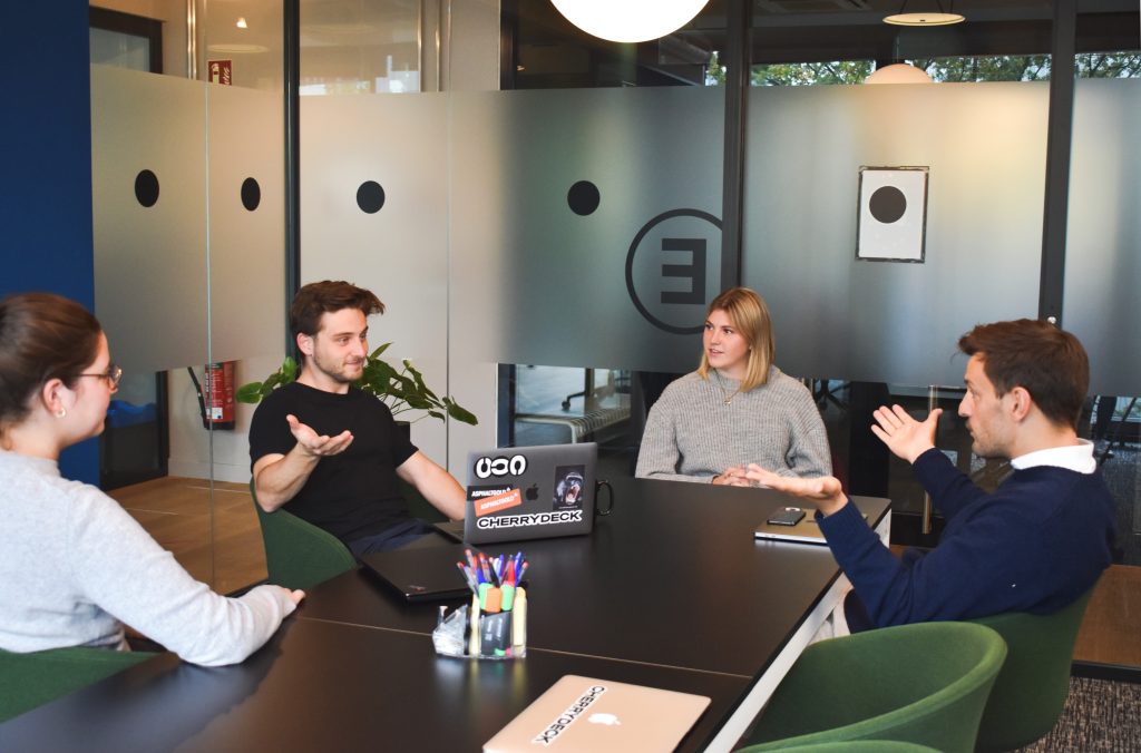 Photo of 4 people in a meeting room discussing