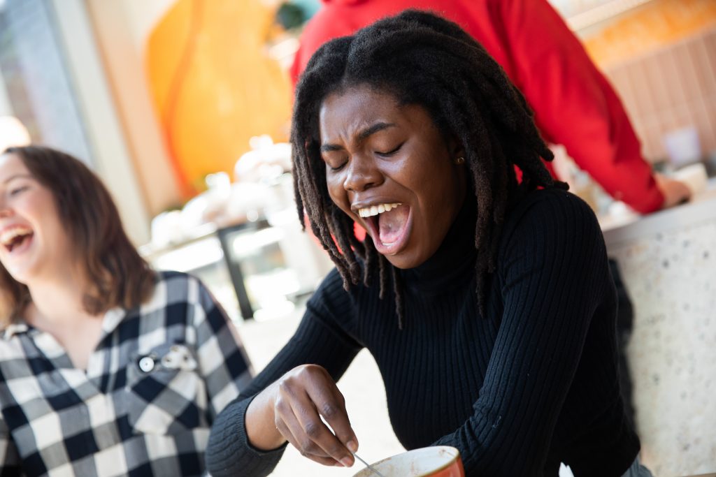 photo of Chidera wearing a black dress having coffee and laughing with friends