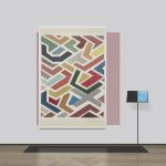 Abstract painting of block colours hanging on a wall with a book on a stand to the right.