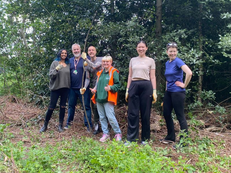 Six people standing in woodland smiling.