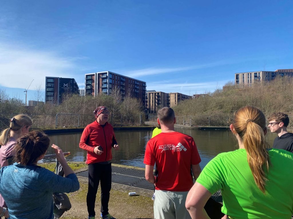 People in running gear on a sunny day in Salford.