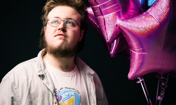 Ben Hodge holding a display of pink and blue balloons, the colours of the Trans flag