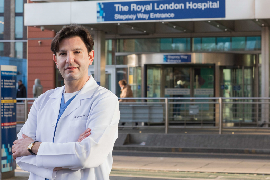 Alex Woodman outside The Royal Oldham Hospital in a lab-coat