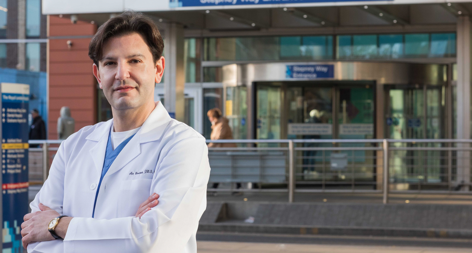 Alex Woodman outside The Royal Oldham Hospital in a lab-coat