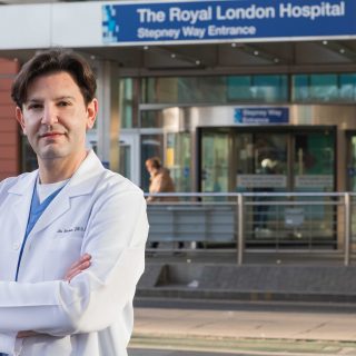 Alex Woodman outside The Royal Oldham Hospital in a lab-coat