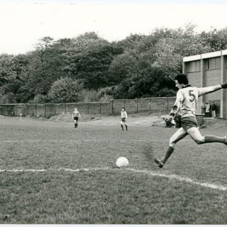 Footballer kicking a ball in the 1970s at the Cliff