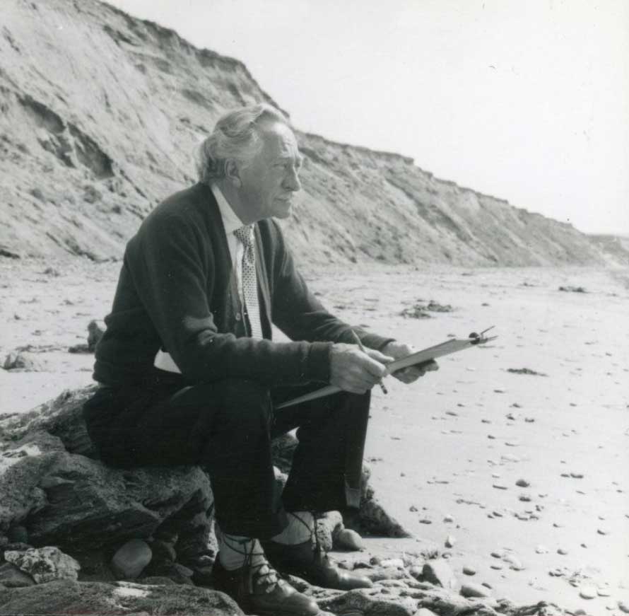 Walter Greenwood sitting on a beach
