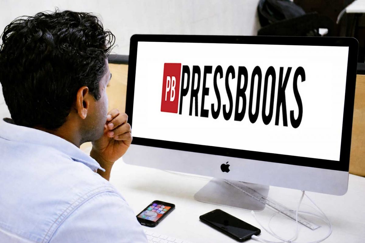 A person reads a screen showing the logo for Pressbooks