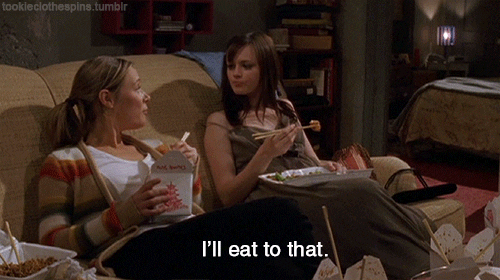 2 girls eating takeaway on a couch