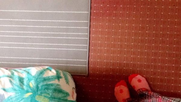 A grey with white lines rug on a floor