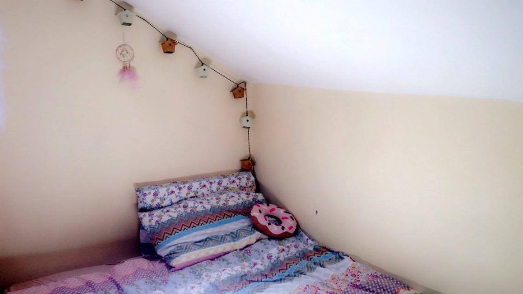 Fairy lights above a bed with purple and blue stripy sheets on