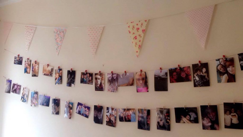 Photos on a wall being held up with small pegs on a string
