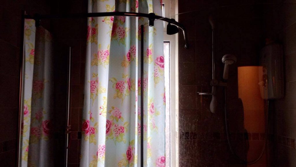 A white shower curtain with pink flowers on it