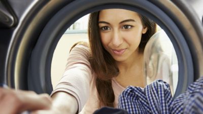 Woman loads washing into a washing machine