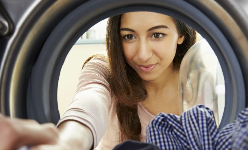 Woman loads washing into a washing machine