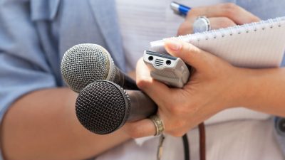 Journalist holding microphones and notepad