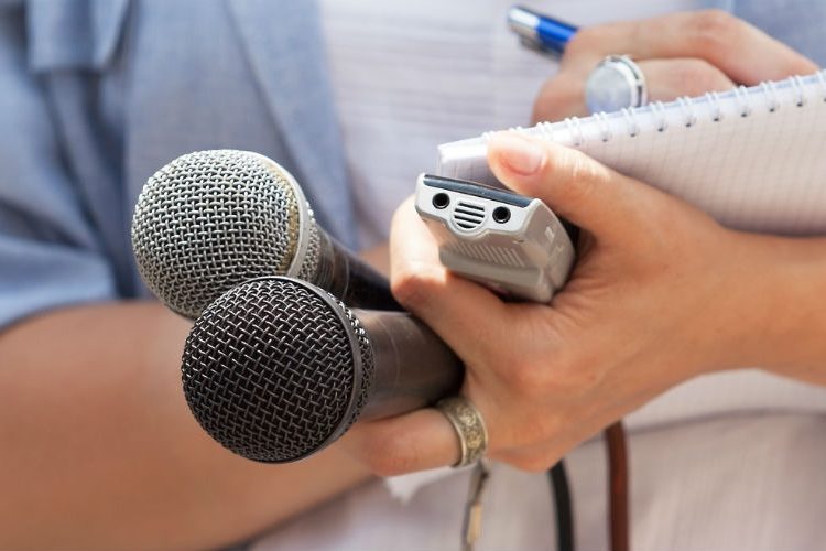 Journalist holding microphones and notepad