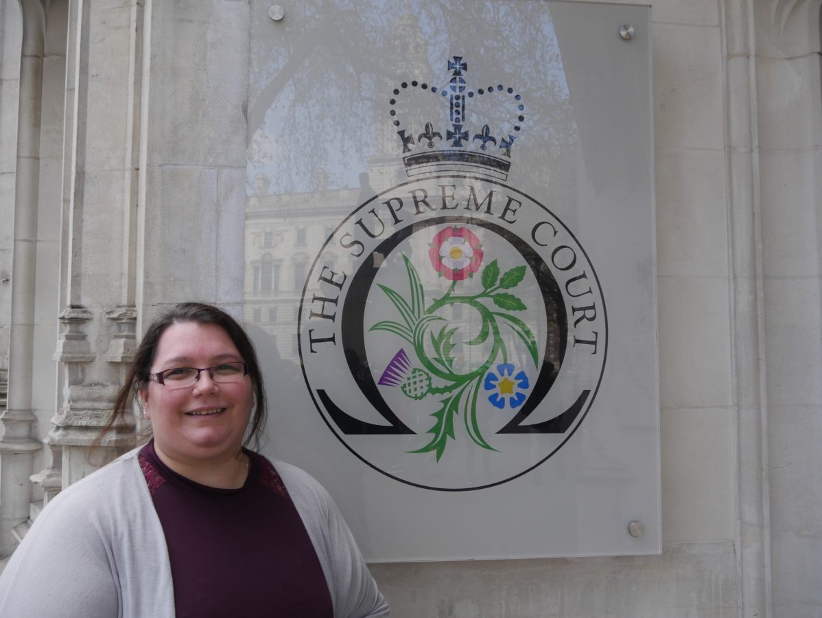 Sarah McCormick in front of the Supreme Court logo on a wall