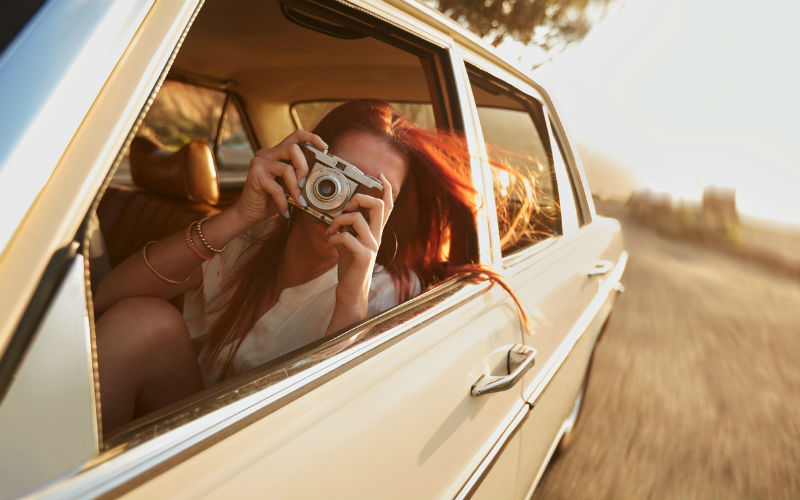 A girl taking photos from a car