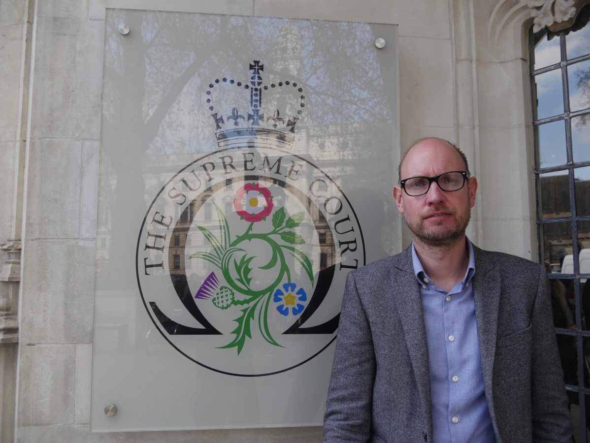 Martin Bate in front of the Supreme Court logo on a wall