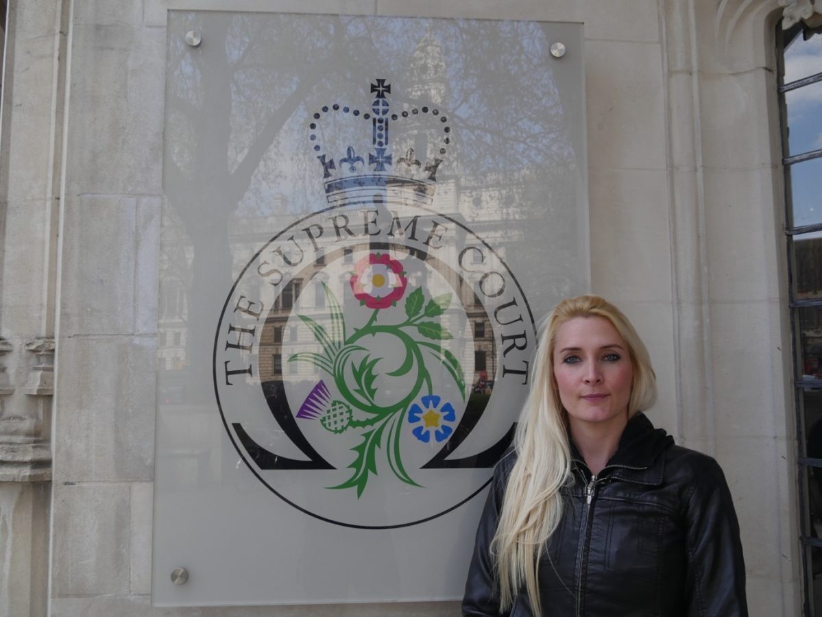 Rachael Stanner in front of the Supreme Court logo on a wall