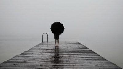 A girl with an umbrella looking at the water