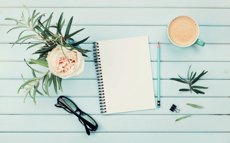 Notebook on a table with flowers and a coffee