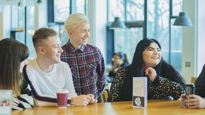 Image; group of student social media assistants sat together in Maxwell cafe.