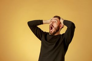 image: Portrait of young man with shocked facial expression over orange studio background