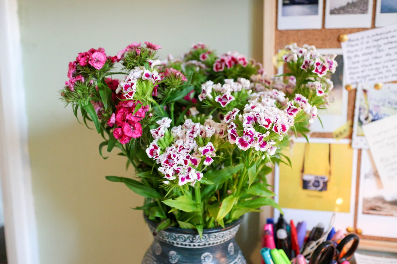A blue vase with white patter around the top containing pink and white flowers