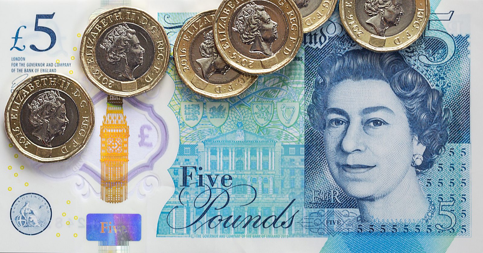 A £5 note with 6 pound coins on top of it
