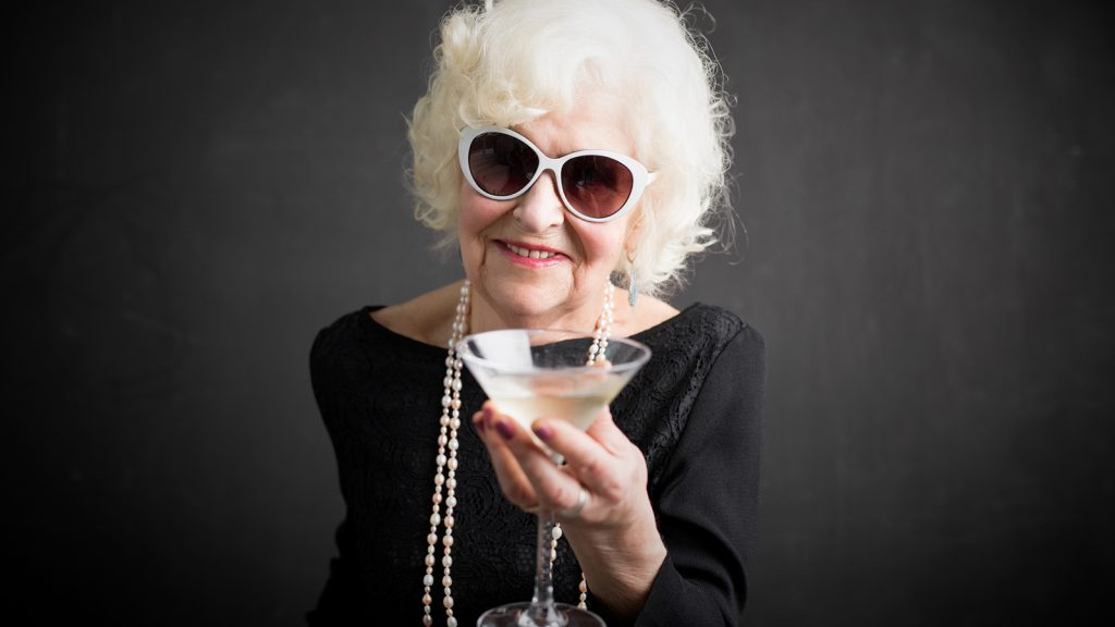 Older lady wearing sunglasses with cocktail in a martini glass