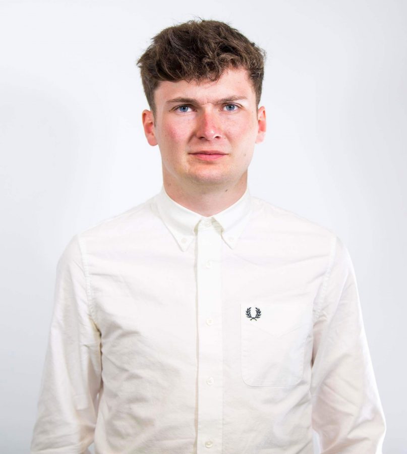 Portrait photo of James Allen wearing a white shirt against a white wall