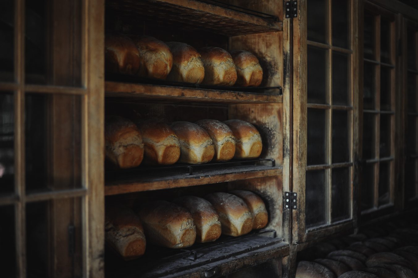 Bread loaves on shelves in a wooden storage cupboard after being bakedx.