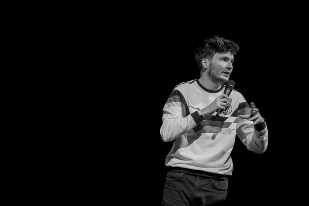 A black and white photo of James Allen performing holding a microphone