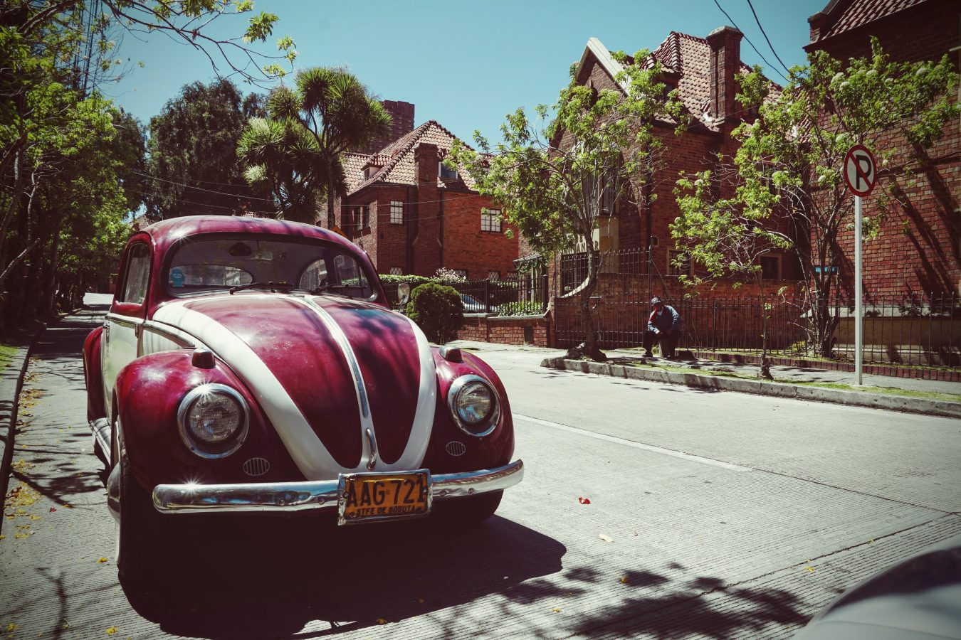 Photo of a 1970's Volkswagen Beatle car coloured red and white, with white stripes going from the centre front to the sides over the bonnet to the white sides.