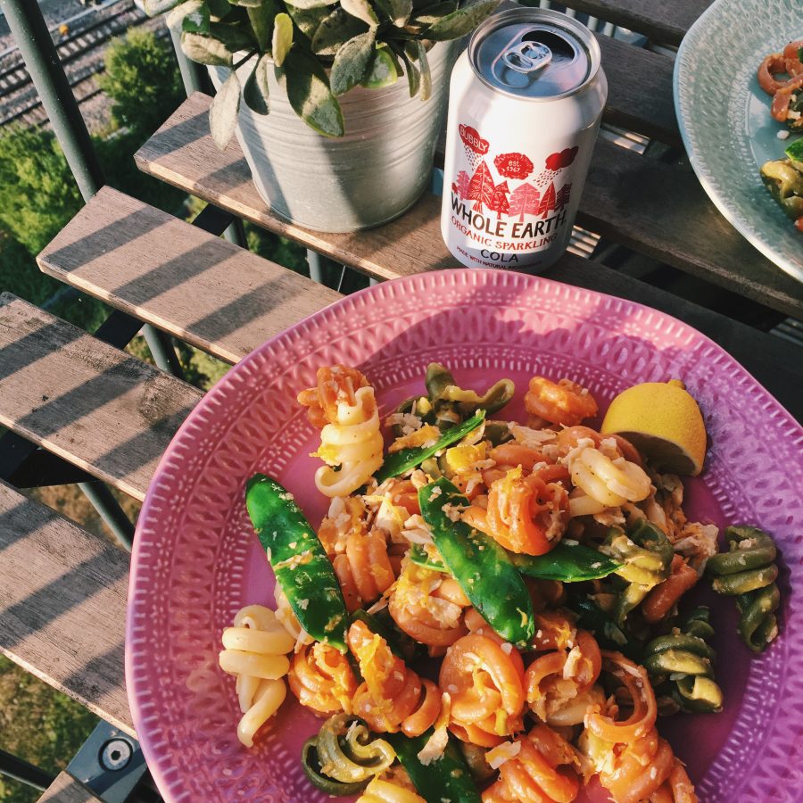 Lemon pasta in a pink bowl on an outside table