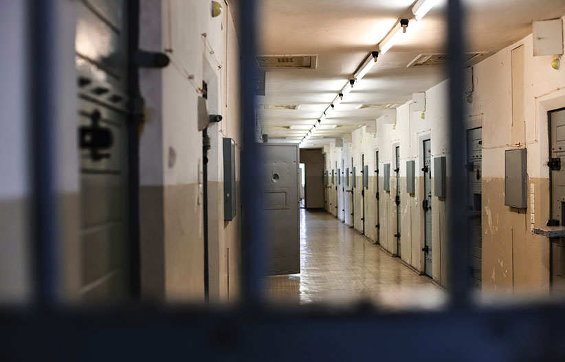 A photo of a prison hallway taken through metal bars.