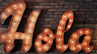 the word 'Hola' in lights on a brick wall