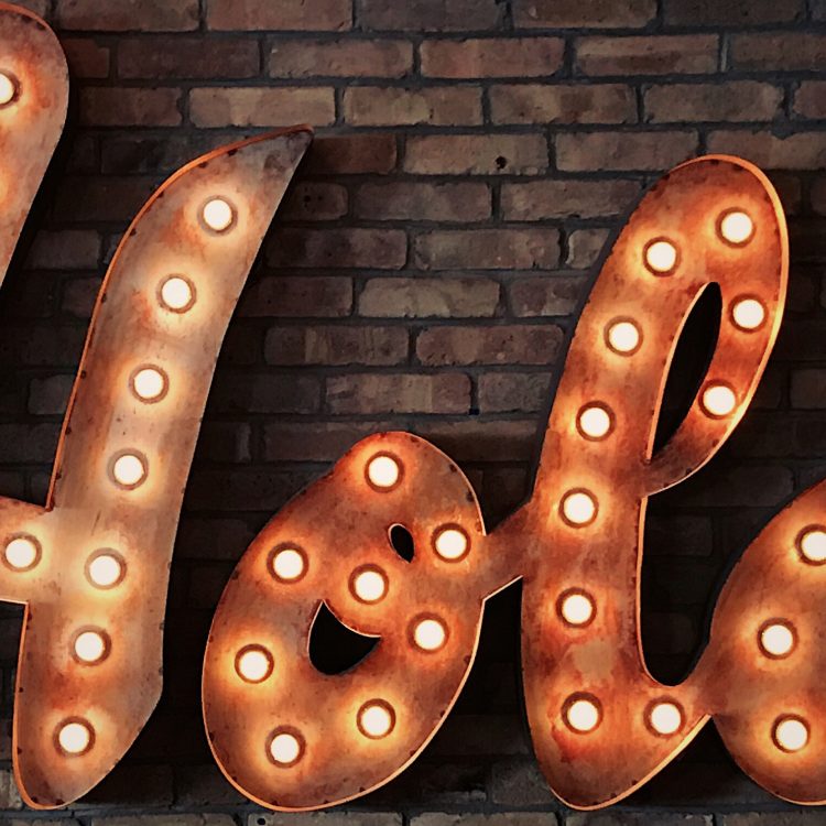 the word 'Hola' in lights on a brick wall
