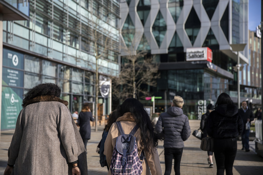 A shot of several students walking towards the University of Salford building in MediaCityUK.