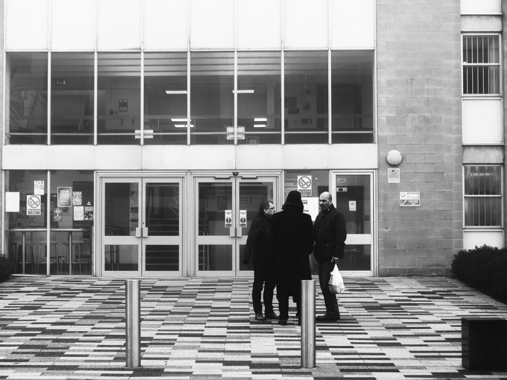 Three people stood outside the Newton Building on the Main University of Salford campus.