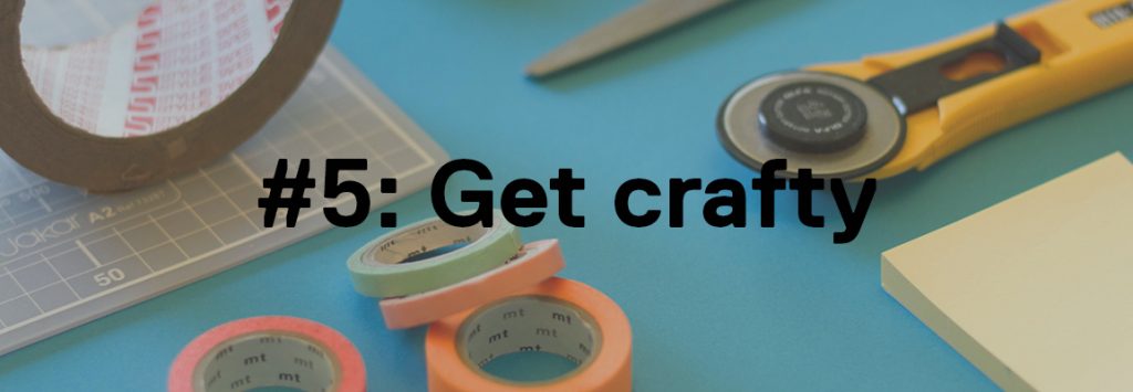 Photo by Jo Szczepanska on Unsplash. In the background you can see on a blue table there is several craftwork tools such as a cutting board, different coloured paper tapes, a big role of brown packing tape, some scissors, a post it note and a cutting tool. In the foreground the text reads '#5: Get crafty'