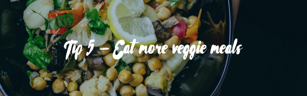 Image source is Photo by Kevin McCutcheon on Unsplash. In the background there is a black bowl filled with a chickpea and vegetable salad or meal. In the bowl you can see chickpeas, mushrooms, onions, greens and a slice of lemon. In the foreground white text reads 'Tip 5 -Eat more veggie meals'.