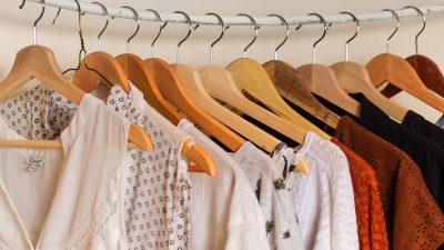 Several pieces of clothing are hung with clothes hangers on a rail
