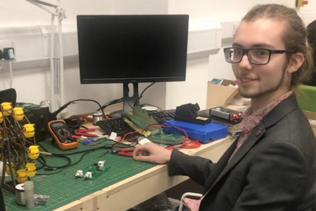 Ivan Holmes posing with his computer and electronic equipment