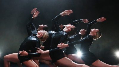 The ensemble of 'Emergence 19/20' performing on stage in black leotards