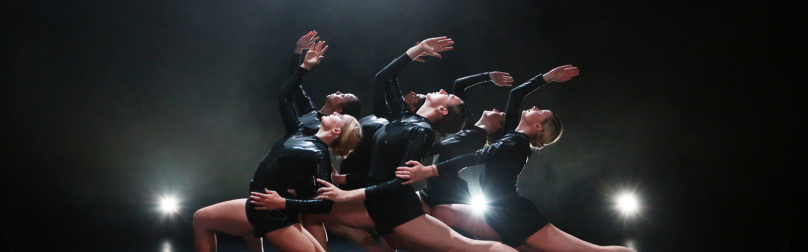 The ensemble of 'Emergence 19/20' performing on stage in black leotards